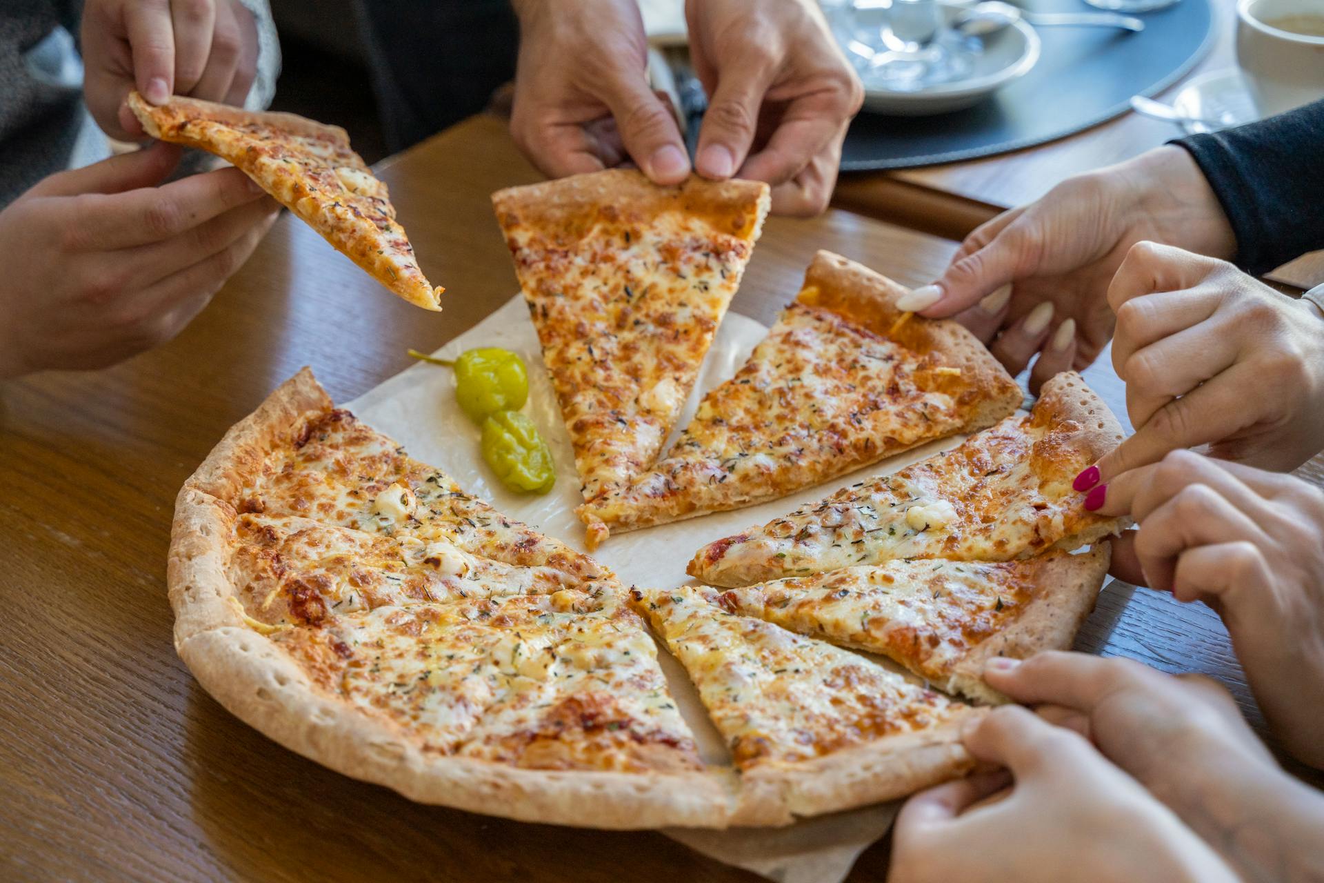 People taking slices of a pizza | Source: Pexels