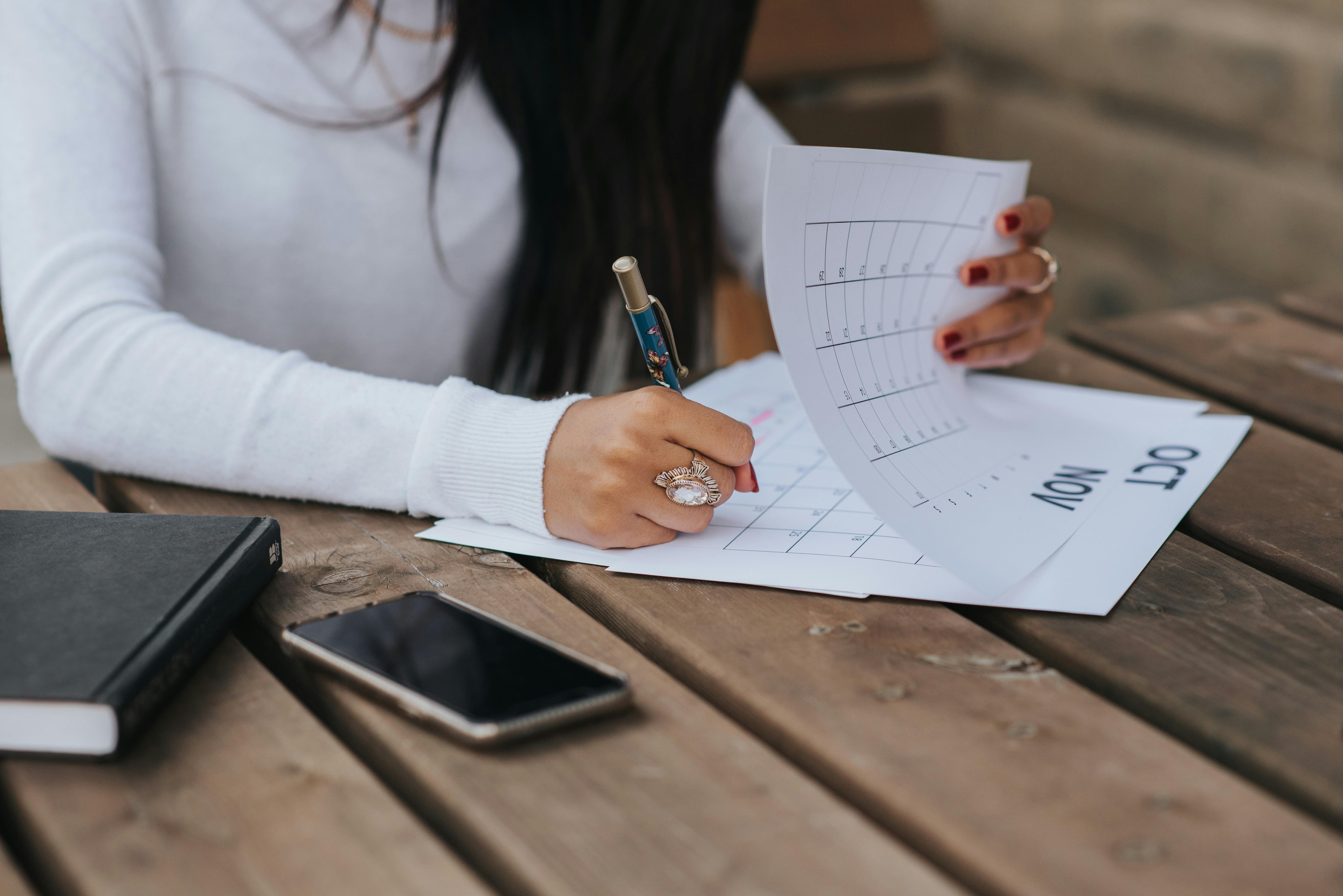 A woman jotting down notes on a calendar | Source: Pexels