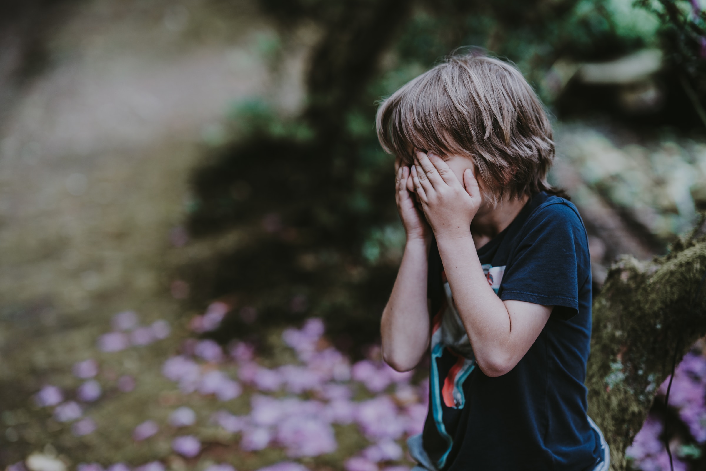 A young boy covering his eyes while crying | Source: Unsplash