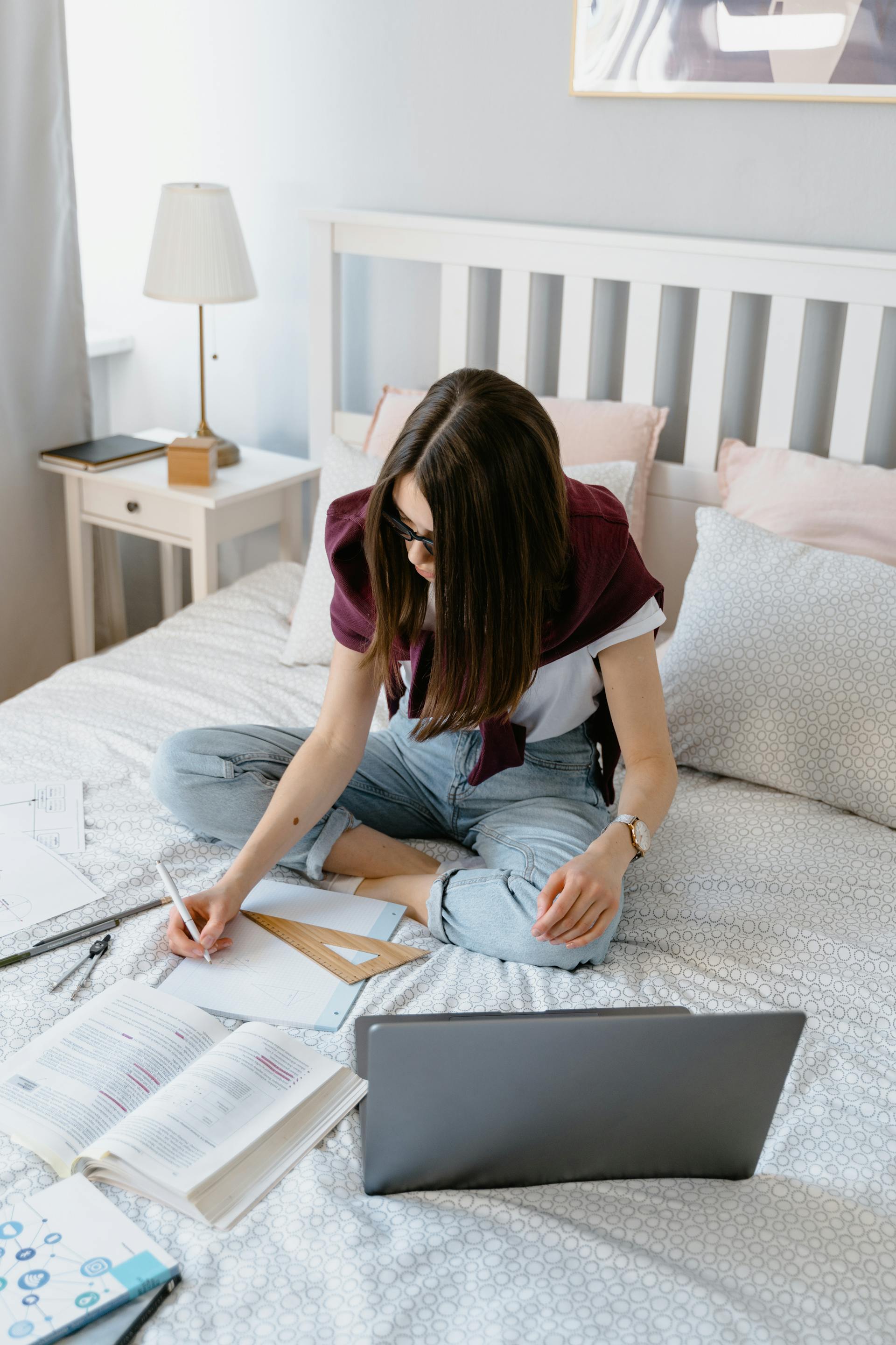 A woman studying while sitting in bed | Source: Pexels