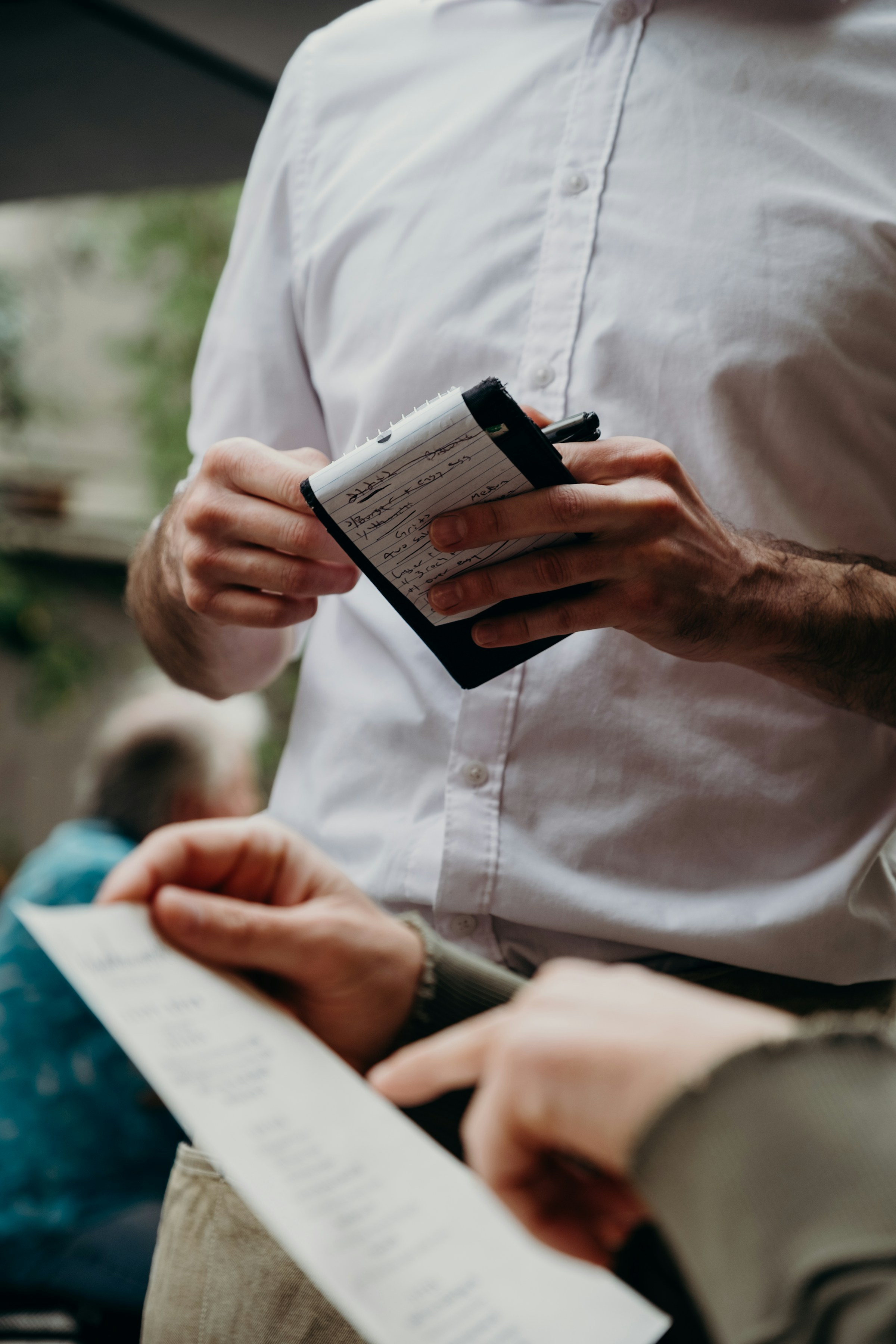 A server in a restaurant standing next to a customer reviewing the bill | Source: Unsplash